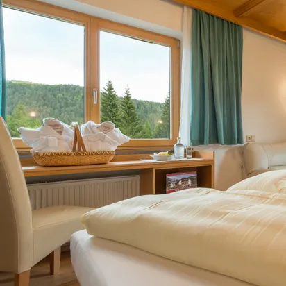 Gemütliches Hotelzimmer mit Bergblick, Doppelbett, Herzkissen und rustikaler Holzdecke